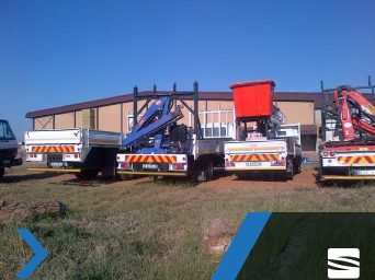 Two Sibinza crane trucks parked on site with booms stowed.