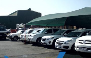 Sibinza vehicle fleet lined up in the yard under a carport.