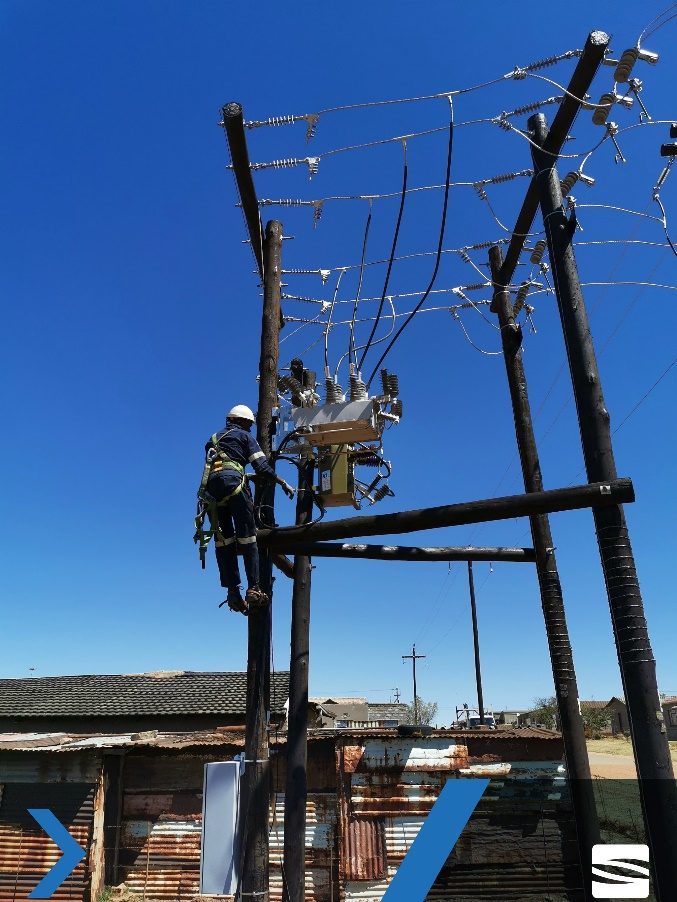 A Sibinza linesman working at height on an energised overhead distribution structure.
